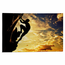 A Silhouette Of Man Climbing On Mountain At Sunset. Adrenaline Rugs 61621308
